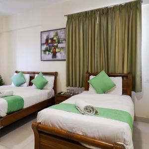 um quarto com 2 camas com almofadas verdes e brancas em Hotel Grand View - Pimple Saudagar em Chinchwad