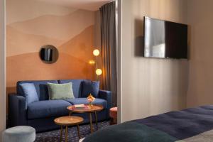 a hotel room with a blue couch and a table at Hôtel Maxim Folies in Paris +17 photos