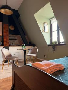 a bedroom with a bed and a table and a kitchen at Apartamenty w centrum Wawel & Smok AC Progres in Toruń
