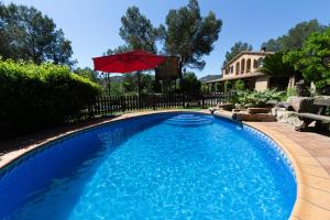 a swimming pool with a red umbrella in a yard at Catalunya Casas Peaceful Perfection , only 30km from Barcelona! in Vacarisas