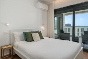 Cama blanca en habitación con ventana grande en Acqua Residence VII - Luxury 3BR in Funchal, en Funchal