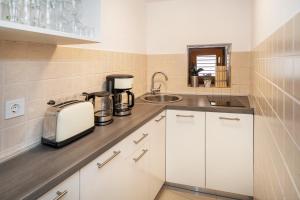 una cucina con mobili bianchi e un lavandino di Apartment Porto with Terrace a Baška