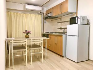 a small kitchen with a table and a refrigerator at Hongshan villa in Osaka