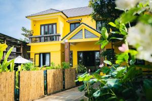 a yellow house with a wooden fence at Aki Eco-villa Hội An in An Bang