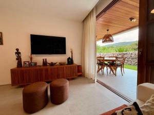 ein Wohnzimmer mit einem TV und einem Tisch mit Stühlen in der Unterkunft Refúgio Elegante e Confortável no Coração da Chapada Diamantina in Mucugê