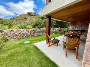 eine Terrasse mit einem Tisch, Stühlen und einer Steinmauer in der Unterkunft Refúgio Elegante e Confortável no Coração da Chapada Diamantina in Mucugê