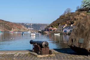 a cannon on the side of a river with boats at Llanfor in Fishguard