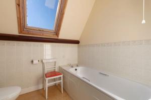 a bathroom with a white tub and a toilet and a stool at Llanfor in Fishguard +12 photos