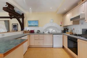a large kitchen with white cabinets and appliances at Llanfor in Fishguard
