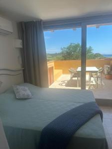 ein Schlafzimmer mit einem Bett und ein Balkon mit einem Tisch in der Unterkunft Appartamento Spiaggia Marinella con vista mare e piscina, Costa Smeralda in Marinella