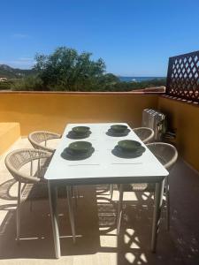 ein weißer Tisch mit vier Tellern darauf auf einer Terrasse in der Unterkunft Appartamento Spiaggia Marinella con vista mare e piscina, Costa Smeralda in Marinella