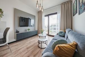 a living room with a blue couch and a tv at Sol Marina by Comfort Apartments in Wiślinka