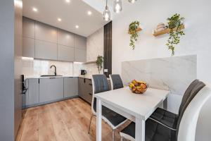 a kitchen and dining room with a white table and chairs at Sol Marina by Comfort Apartments in Wiślinka +14 photos