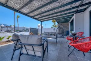 a patio with red chairs and a table at Casa Eva - Private Pool, BBQ & Free Parking By Lanzarote Vacation Homes in Los Pocillos