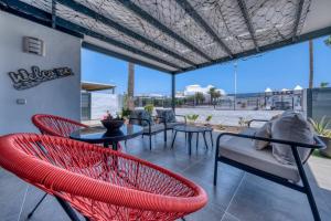 a patio with red chairs and tables and windows at Casa Eva - Private Pool, BBQ & Free Parking By Lanzarote Vacation Homes in Los Pocillos