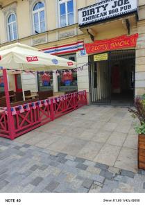 a red table with an umbrella in front of a building at Apartament Centrum Lublin in Lublin