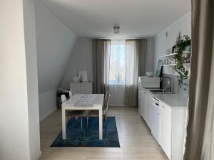 a white kitchen with a table and a kitchen counter at Pokoje z łazienką przy Porcie Genaker w Giżycku in Giżycko