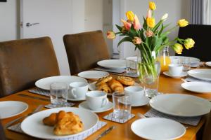 een tafel met witte borden en gebak en een vaas met bloemen bij Brambly Cottage in Whitby