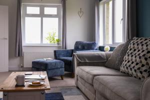 een woonkamer met een bank en 2 blauwe stoelen bij Brambly Cottage in Whitby