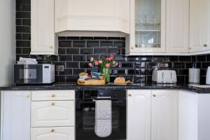 een keuken met witte kasten en zwarte tegels bij Brambly Cottage in Whitby +44 foto's