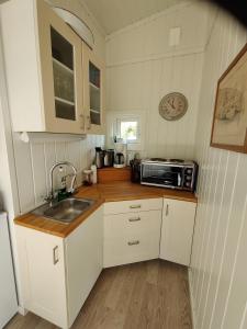 eine kleine Küche mit Spüle und Mikrowelle in der Unterkunft Sjarmerende liten gjestehytte in Fredrikstad + 8 Fotos