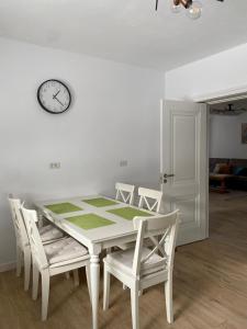 a dining room table with chairs and a clock on the wall at Casa Mălina Putna in Putnişoara +61 photos