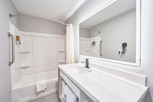 a white bathroom with a sink and a mirror at All Seasons Inn & Suites in Bourne