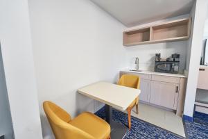 a small kitchen with yellow chairs and a table at The Bridgeway in Bourne