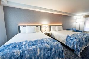 a hotel room with two beds with blue and white sheets at The Bridgeway in Bourne