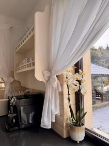 a window with a curtain and flowers in a kitchen at Casa Mălina Putna in Putnişoara