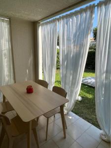 une table et des chaises devant une fenêtre avec des rideaux blancs dans l'établissement Appartement rénové avec piscine, plage 2mns à pied, au Cap d'Agde 3 autres photos