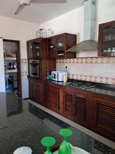 a kitchen with wooden cabinets and green stools at J and R Villa, Watamu in Watamu