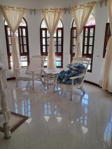 a living room with chairs and a table and windows at J and R Villa, Watamu in Watamu