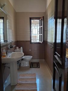 a bathroom with a sink and a toilet and a window at J and R Villa, Watamu in Watamu