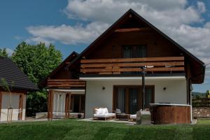 a house with a pitched roof with a lawn at Leśne Chatki - domek Jodła in Koniaków