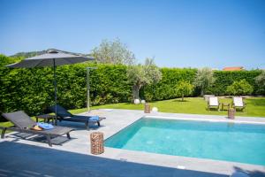 una piscina con mesa, sombrilla y sillas en Filerimos Panorama Villa, en Pastida