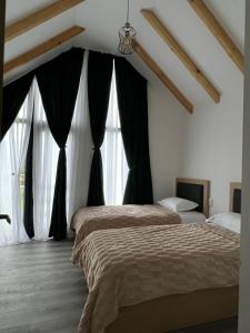 two beds in a bedroom with black curtains at MTA house - Borjomi in Borjomi