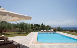 a swimming pool with chairs and an umbrella at Hegemoni Villa Porto Heli in Porto Heli