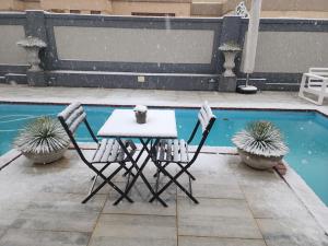 a table and two chairs next to a pool at NobelAqua Suites in Maseru +20 photos