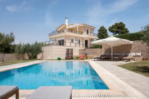 a swimming pool in front of a house at Hegemoni Villa Porto Heli in Porto Heli
