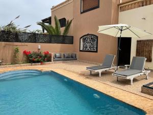 a swimming pool with two chairs and an umbrella at Modern villa with pool in Mirleft