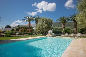 a swimming pool with a fountain and palm trees at Masseria Galleppa by Apulia Hospitality in Monopoli