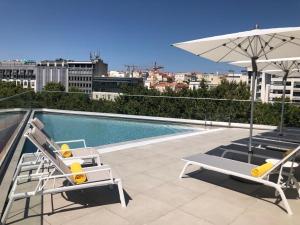 a swimming pool with two chairs and an umbrella at TURIM Boulevard Hotel in Lisbon
