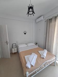 a white bedroom with a large bed with white pillows at Eleni's seaside home in Asprovalta