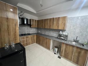 a kitchen with wooden cabinets and a black refrigerator at Royal BNB Two BedRoom Luxury Apartment in Lahore