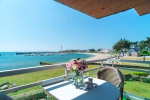 a table with a vase of flowers sitting on a balcony at Le Mayalou - Vue Mer in Sarzeau