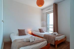 two beds in a room with a window at Le Mayalou - Vue Mer in Sarzeau