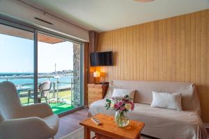 a living room with a couch and a table with a vase of flowers at Le Mayalou - Vue Mer in Sarzeau