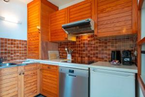 a kitchen with wooden cabinets and a white refrigerator at Le Mayalou - Vue Mer in Sarzeau +5 photos