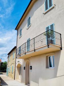 a white building with a balcony on the side of it at Conti di San Bonifacio - Tuscan Townhouse in Montemassi